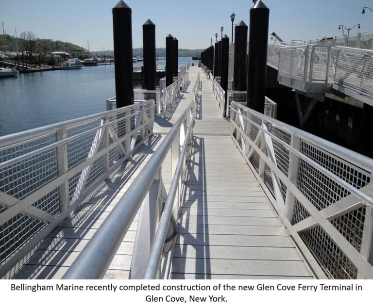 The Glen Cove floating ferry terminal with a modern dock structure extending over calm waters, surrounded by a scenic coastal