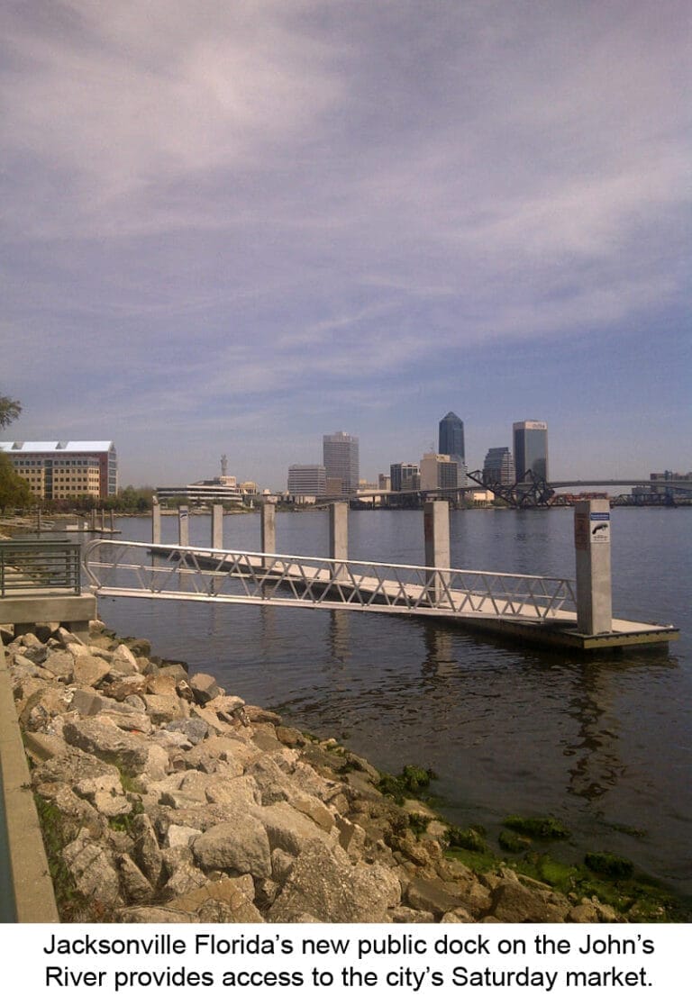 A public dock on a river with people walking and boats moored, enhancing Jacksonville public dock access.