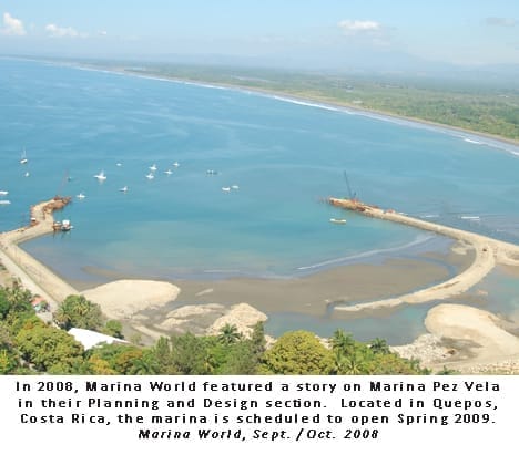 Boats docked at Marina Pez Vela sportfishing harbor with lush green hills in the background under a clear blue sky.