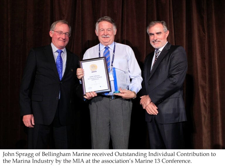John Spragg marina industry contribution - John Spragg smiles while holding an award plaque, recognized for his marina indust