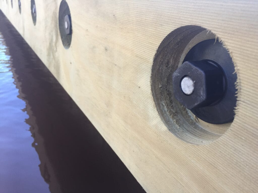 Close-up of FRP rods for pontoon construction with non-ferrous nuts, showcasing composite mix and thread design.